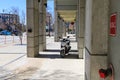 A white and black motor scooter parked on a sidewalk surrounded by concrete pillars in downtown Atlanta