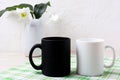 White and black mug mockup with lily in vase Royalty Free Stock Photo