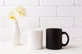 White and black mug mockup with soft yellow orchid in vase Royalty Free Stock Photo