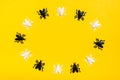 White and black plastic flies lie in a circle on a yellow cardboard background. Ready Halloween invitation