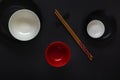 White, black and red empty plates with chopsticks in an oriental style lie on a dark table in a minimalist composition. Royalty Free Stock Photo