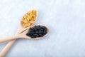 White and Black seedless raisins in wooden spoons on grey background. Selective focus, copy space. Dried dehydrated grapes fruit, Royalty Free Stock Photo