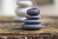 White black stone cairns, poise light pebbles on wood stump in front of brown natural background, zen like, harmony and balance Royalty Free Stock Photo