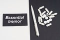 On a white and black surface are pills, a pen and a sign with the inscription - essential tremor Royalty Free Stock Photo