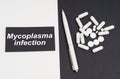 On a white and black surface are pills, a pen and a sign with the inscription - Mycoplasma Infection Royalty Free Stock Photo