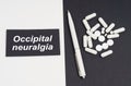 On a white and black surface are pills, a pen and a sign with the inscription - Occipital neuralgia