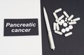 On a white and black surface are pills, a pen and a sign with the inscription - Pancreatic cancer