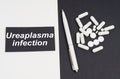 On a white and black surface are pills, a pen and a sign with the inscription - Ureaplasma infection