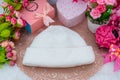 White blank beanie above a small round tablecloth hat surrounded by gift boxes and flowers Royalty Free Stock Photo