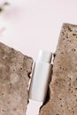 White blank bottle of cosmetic product between grey pieces of concrete material