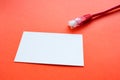 A white blank business card out of focus in the foreground and a connector with an Internet cable in the background in red Royalty Free Stock Photo