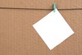 White blank card on rope on a brown cardboard background. Creati Royalty Free Stock Photo