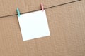 White blank card on rope on a brown cardboard background. Creati Royalty Free Stock Photo