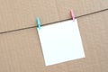 White blank card on rope on a brown cardboard background. Creati Royalty Free Stock Photo