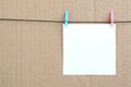 White blank card on rope on a brown cardboard background. Creati Royalty Free Stock Photo