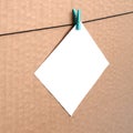 White blank card on rope on a brown cardboard background. Creati Royalty Free Stock Photo