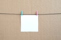 White blank card on rope on a brown cardboard background. Creati Royalty Free Stock Photo