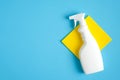 White blank cleaning spray bottle with detergent and yellow rag on blue background. House cleaning service and housekeeping Royalty Free Stock Photo