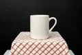 A white blank coffee mug on the top of a hand cloth isolated with black color as the background Royalty Free Stock Photo