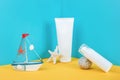 White blank cosmetic tube, bottle with sunscreen, sun cream, moisturizing lotion, starfish, rock and small boat on blue, yellow Royalty Free Stock Photo