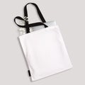 White blank cotton eco tote bag with black straps and little label, laptop and flowers inside. Design mockup