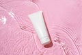 White blank cream tube on a pink background with water waves. Concept of cosmetics for beauty, salon skin care. Image for your Royalty Free Stock Photo