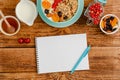 White blank of food diary, healthy breakfast of granola with fruits, milk and honey on wooden table. Royalty Free Stock Photo