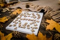 White blank notebook and pen with wooden letters the word autumn on a dark background with a scarf, plaid and a cup, autumn yellow Royalty Free Stock Photo