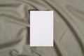 White blank paper card mockup on green neutral colored textile