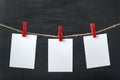 White blank paper cards hang with clothespins on rope. Black background. Copy space, mockup Royalty Free Stock Photo