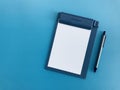 White blank paper on clipboard and grey pen put on blue background Royalty Free Stock Photo