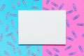 A4 white blank paper Place on a pink and blue background with a scattering of blue and pink paper clips, top view, copy space