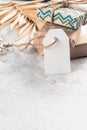 White blank paper tag on craft gifts boxes and Christmas decor on grey conkrete background.