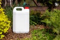 White blank plastic jerry can for garden plant fertilizer in flower bed