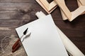 A white blank rectangular primed canvas, roll, palette knives and stretchers lying on a brown wooden background. Top view