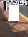 White blank sandwich board sign on a brick sidewalk near a driveway Royalty Free Stock Photo