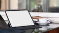White blank screen computer tablet with keyboard case putting on office glass table with coffee cup and stack of books. Royalty Free Stock Photo