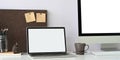 A white blank screen laptop is putting on a white working desk surrounded by office equipment Royalty Free Stock Photo