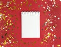 White blank sheet of notebook on a red background with scattered confetti. Holiday education concept. Stock photo. Royalty Free Stock Photo