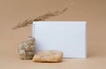 White blank sheet of notepad, stones, dry sprig of grass, on beige background. Copy space, template for your ad, mockup Royalty Free Stock Photo
