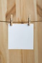 White blank sheet of paper hanging with clothespins on rope on wooden background. Copy space, mockup. Vertical frame Royalty Free Stock Photo