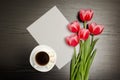 White blank sheet of paper, pink tulips and a mug of coffee. Black table. top view Royalty Free Stock Photo