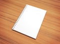 White blank spiral notepad on wooden desk texture.