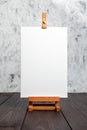 White blank synthetic canvas stretched on subframe and an easel standing on a brown wooden table