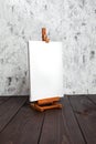 White blank synthetic canvas stretched on subframe and an easel standing on a brown wooden table