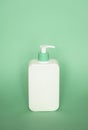 White blank unbranded cosmetic plastic bottle with dispenser pump on green background. Liquid container for shampoo, gel Royalty Free Stock Photo