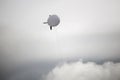 White blimp high in the grey sky