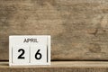 White block calendar present date 26 and month April on wood background