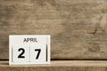 White block calendar present date 27 and month April on wood background