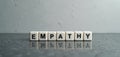 White blocks form the word empathy on a reflective grey surface. Cubes spell out the concept of understanding and connection. Royalty Free Stock Photo